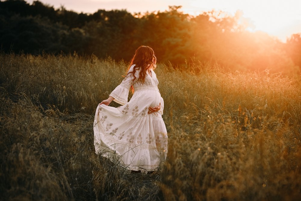 Outdoor Maternity photoshoot in Columbus Ohio with a women pregnant and posing in a gown in a field