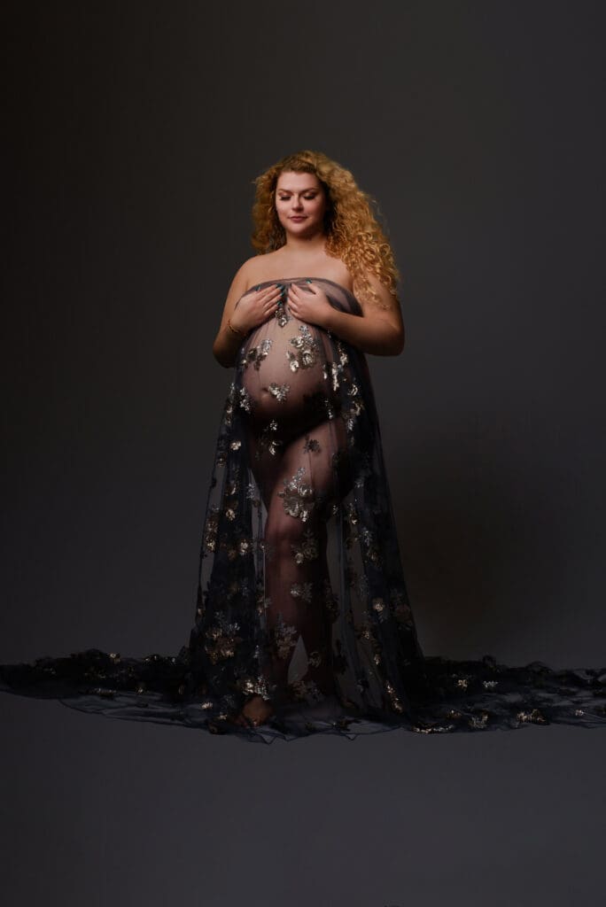 Maternity Photographer in Columbus Ohio shows a women in her photography studio with a pregnant belly and material over top