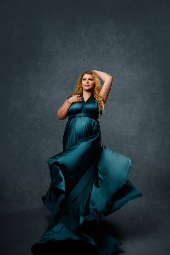 A women posed in a green flowy gown during her maternity photography session in Columbus Ohio