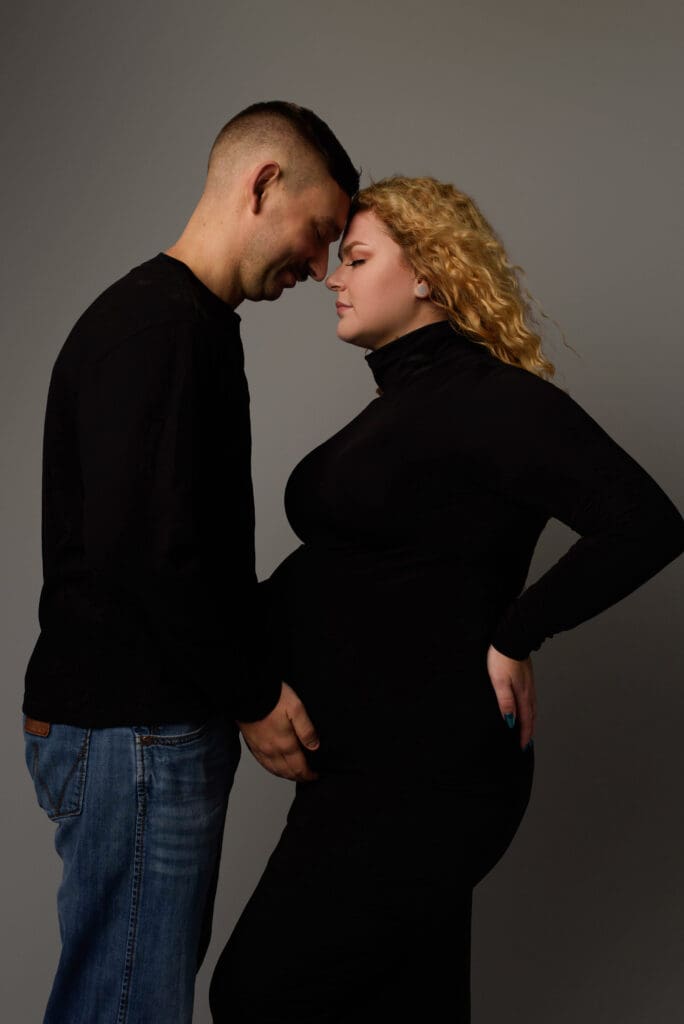 husband looks down at wife and hold her pregnant belly during a maternity photoshoot in Columbus Ohio