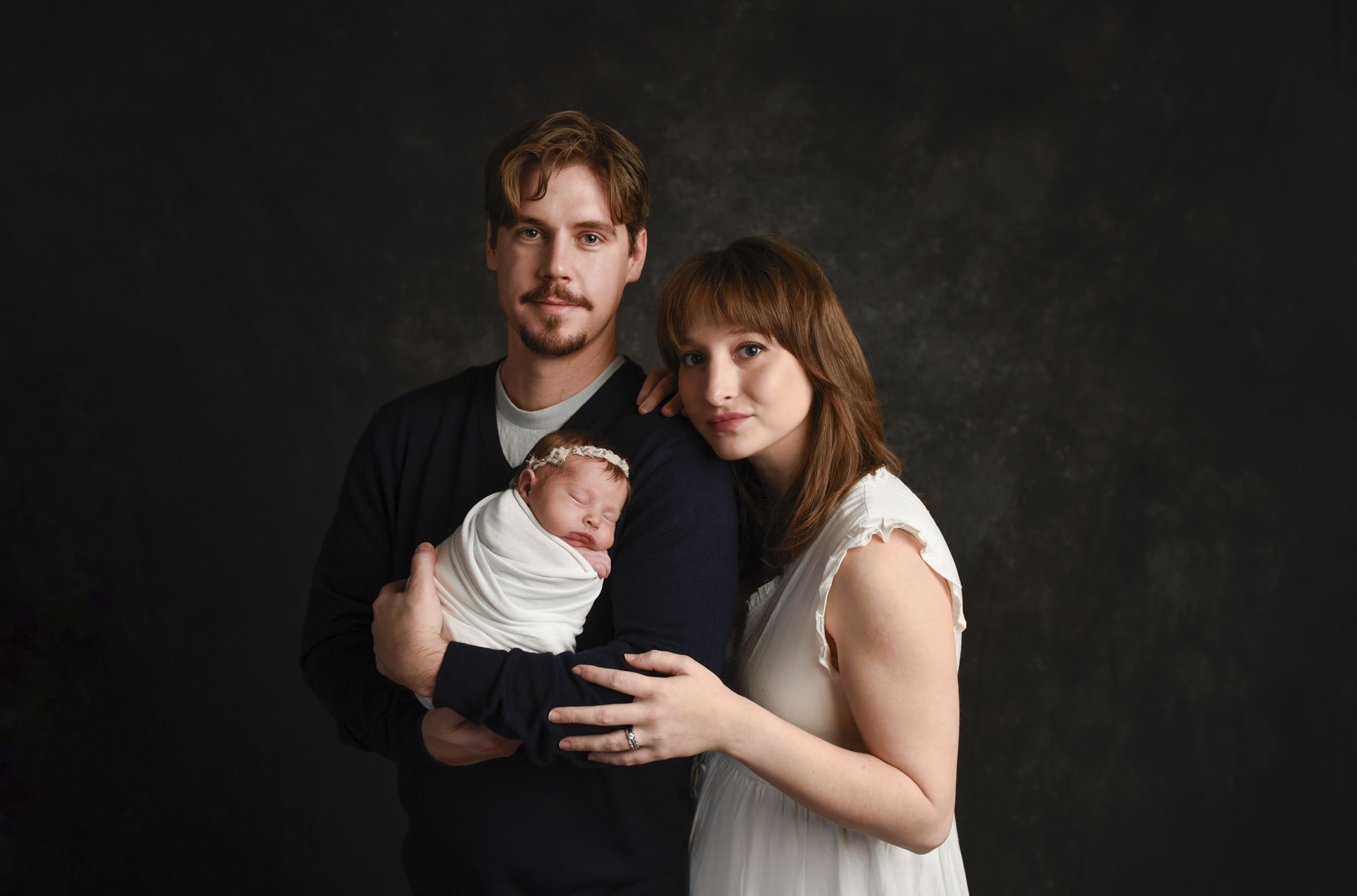 columbus newborn photographer whispyshadesphotography 55 Luxury coupld posing serious with their newborn girl staring at the camera while they have them in the middle