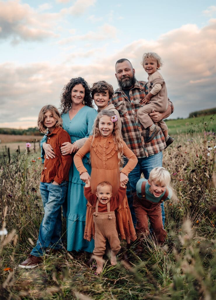 family of 8 wearing fall colors with their children surrounding them