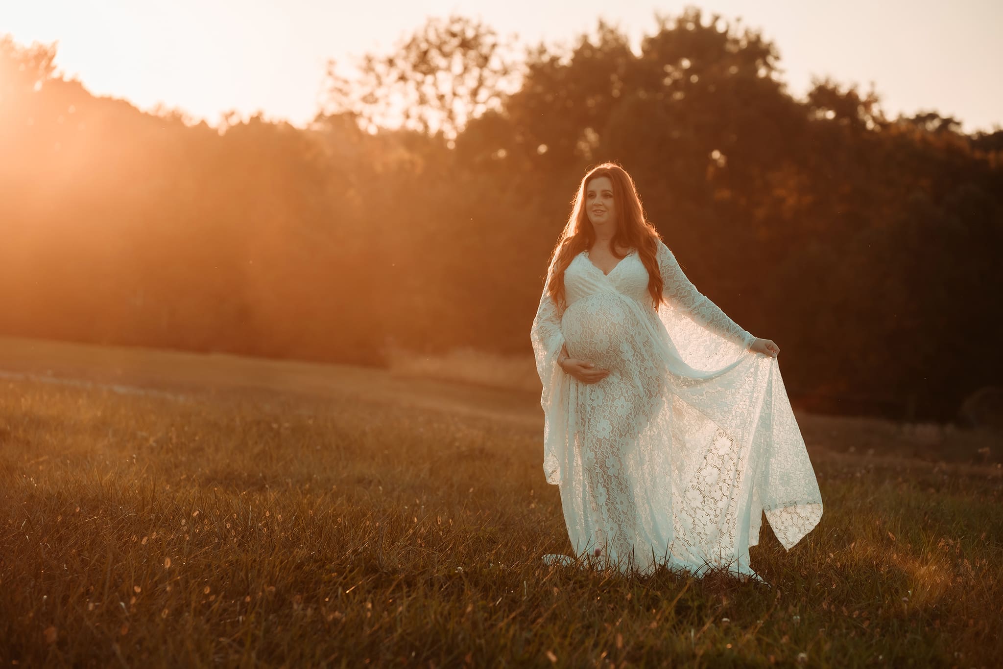 columbus ohio maternity photographer 20 Golden hour with sun flare of pregnant woman holding her belly in a cream gown