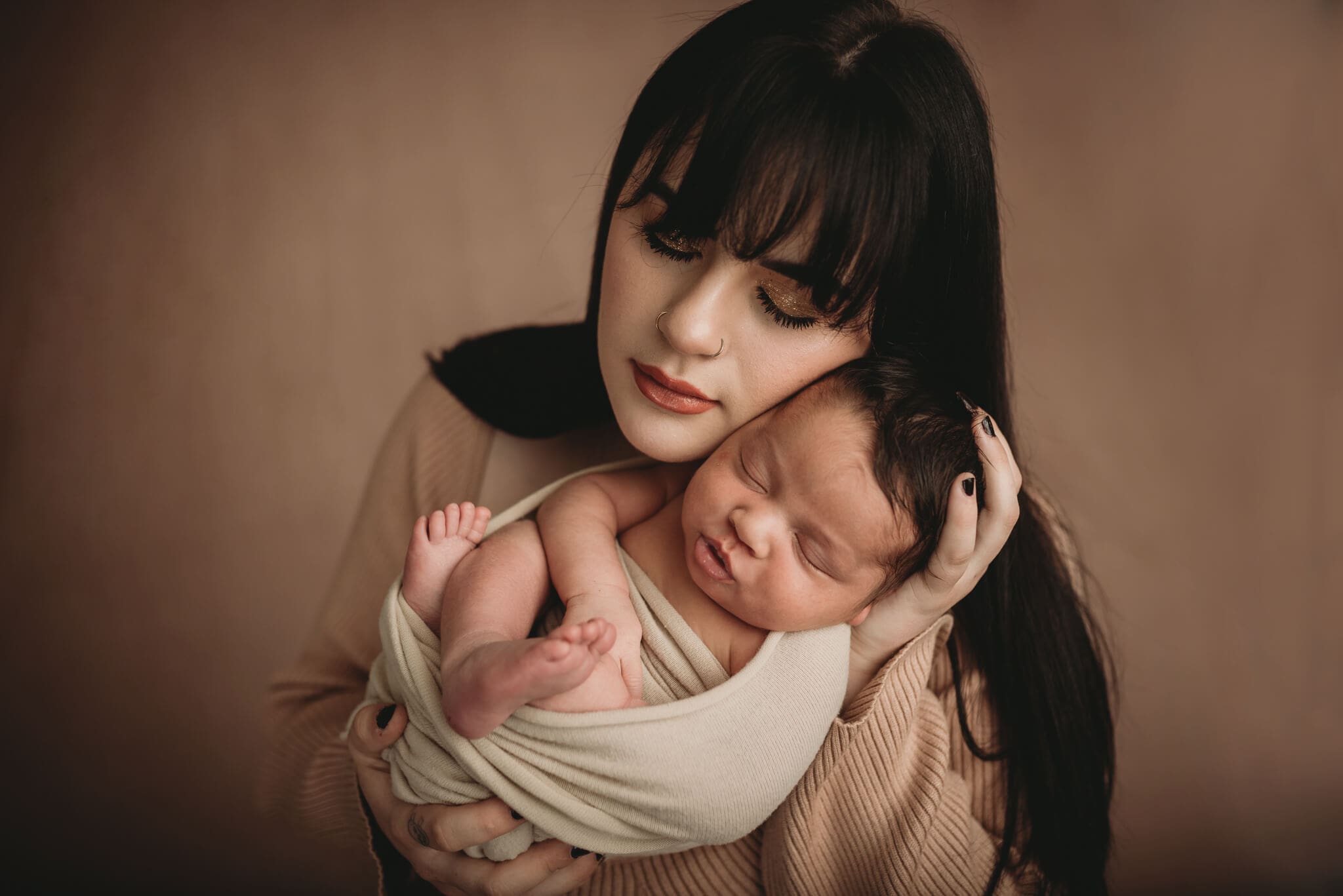 columbus ohio newborn photographer0118 mom holding newborn baby by her face with eyes closed, baby boy wrapped tightly in moms hands