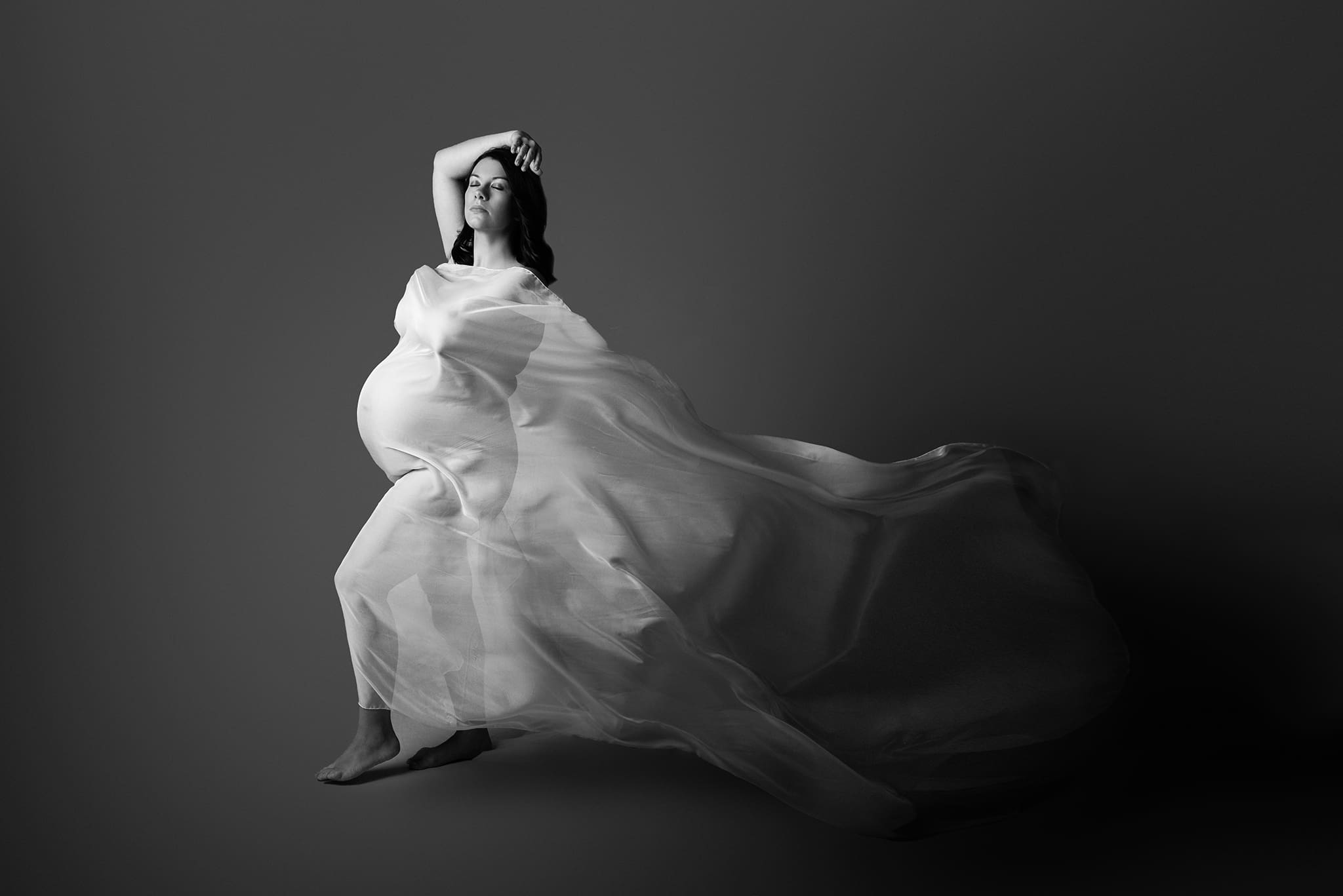 mother to be walking towards the light with white fabric wrapping around her