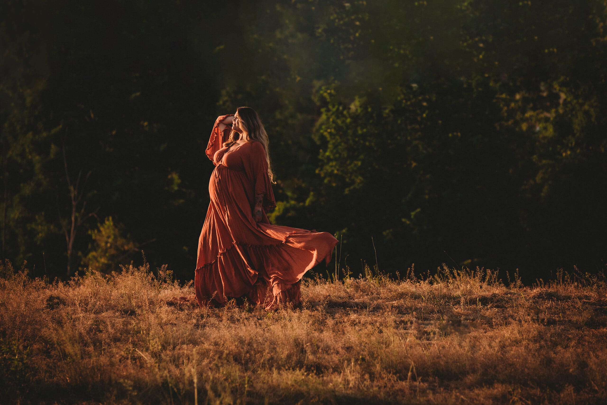 outdoor sunset maternity session with burnt orange linen dress on looking off into the sunset