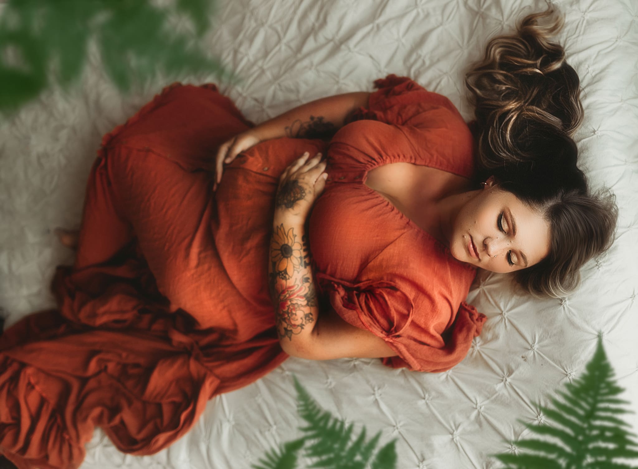 boho maternity studio mother holding her belly with her eye closed laying on her back