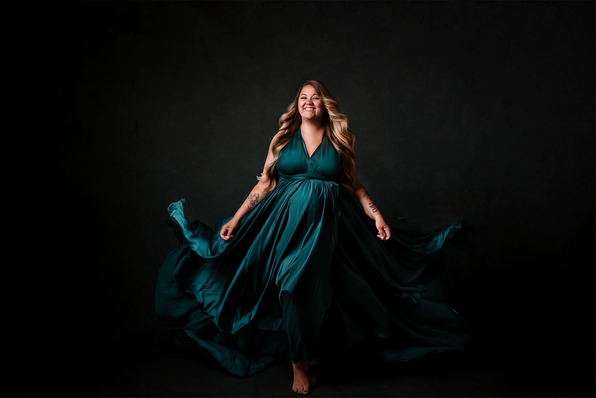 fine art maternity studio session with mom in teal flowing dress walking toward the camera
