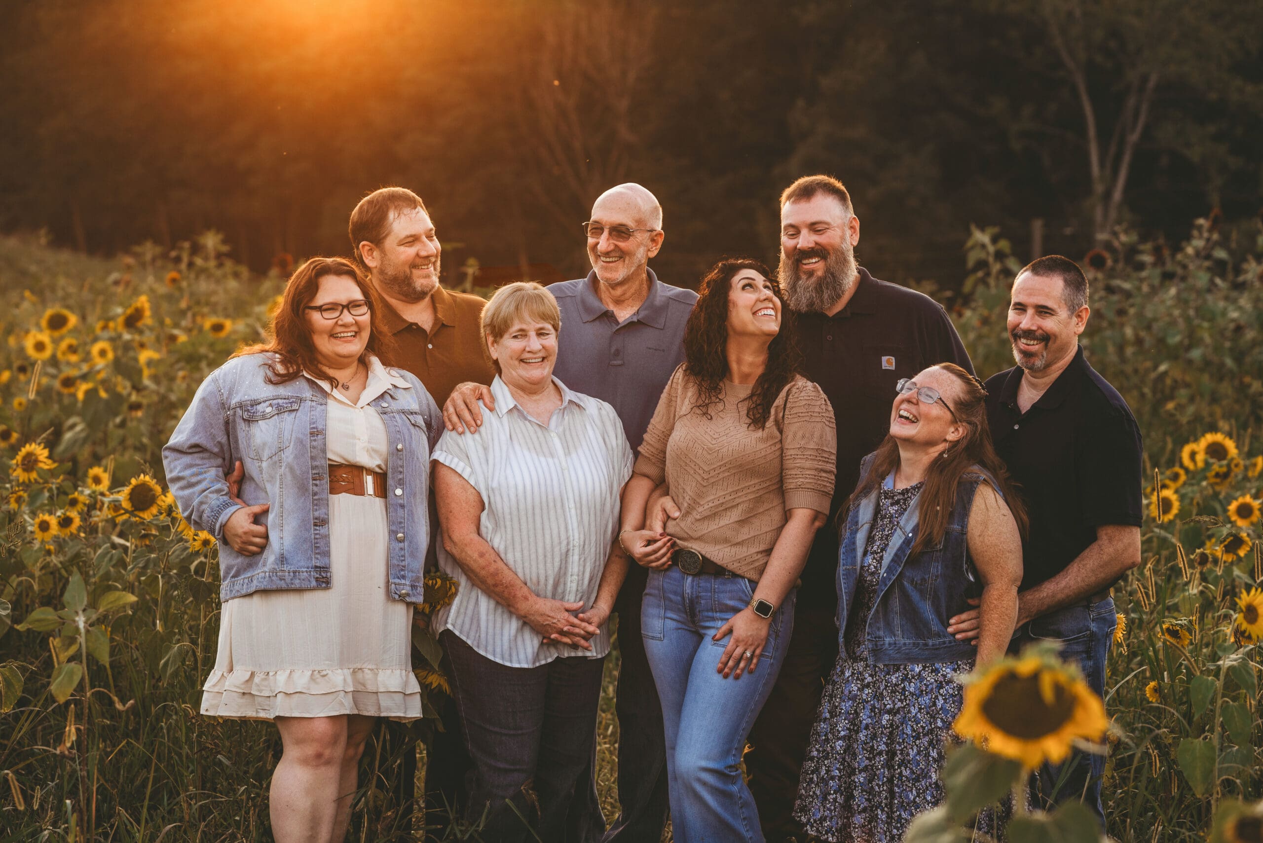 family in the sunflowers at sunset laughing with each other